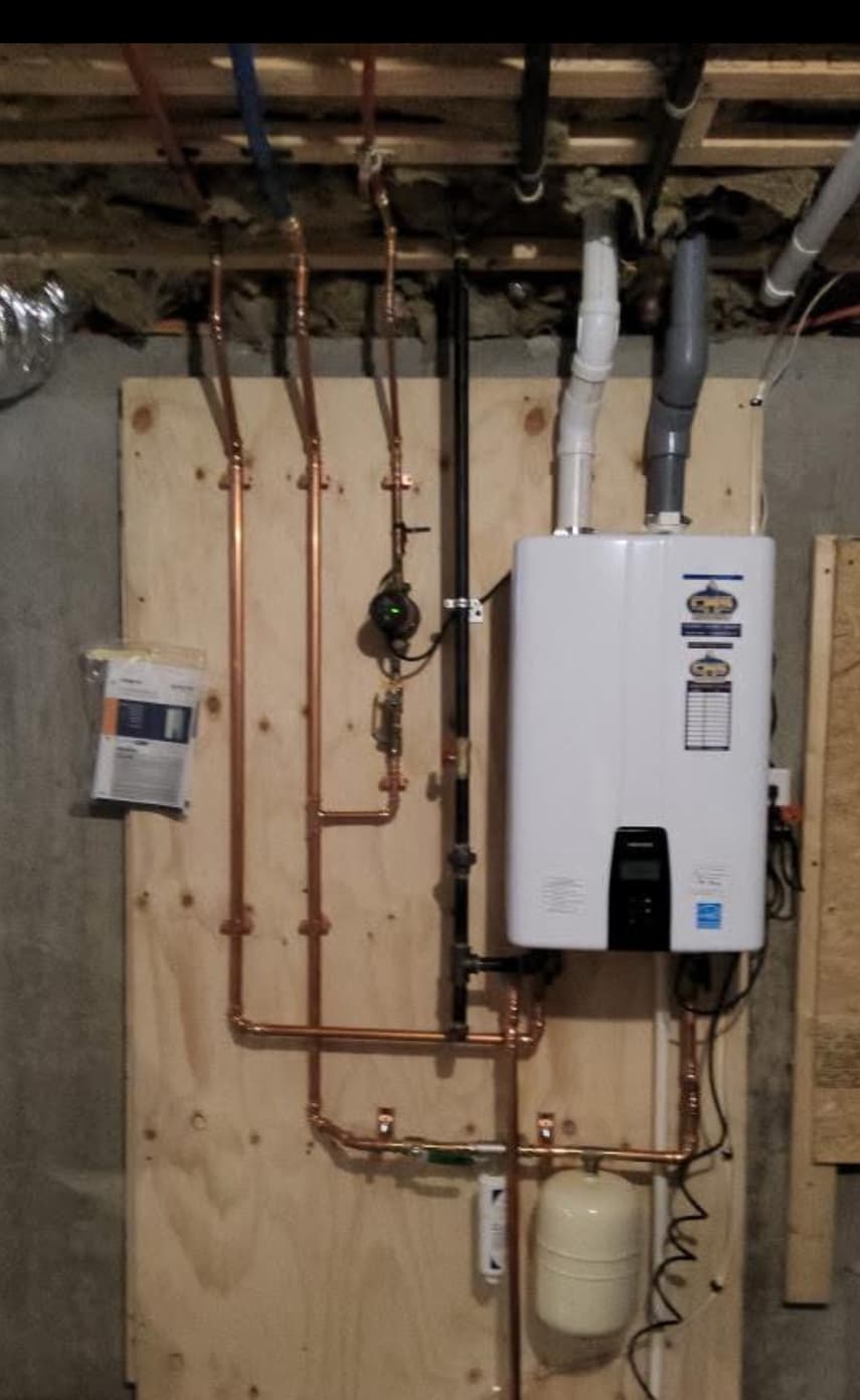 Wall-mounted Navien tankless water heater with clean copper manifold and expansion tank — recent Leawood install